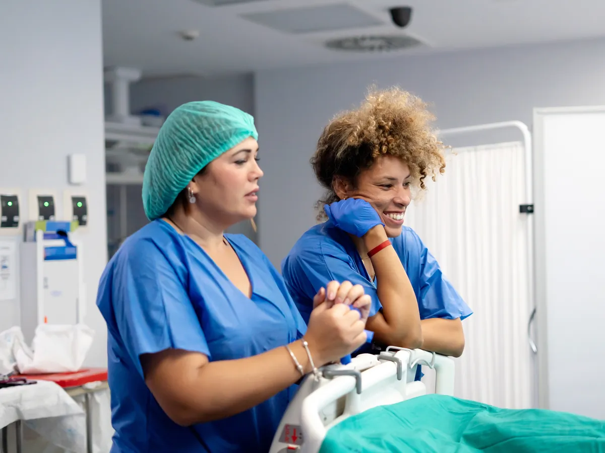 Two healthcare professionals in scrubs sharing a supportive moment at work