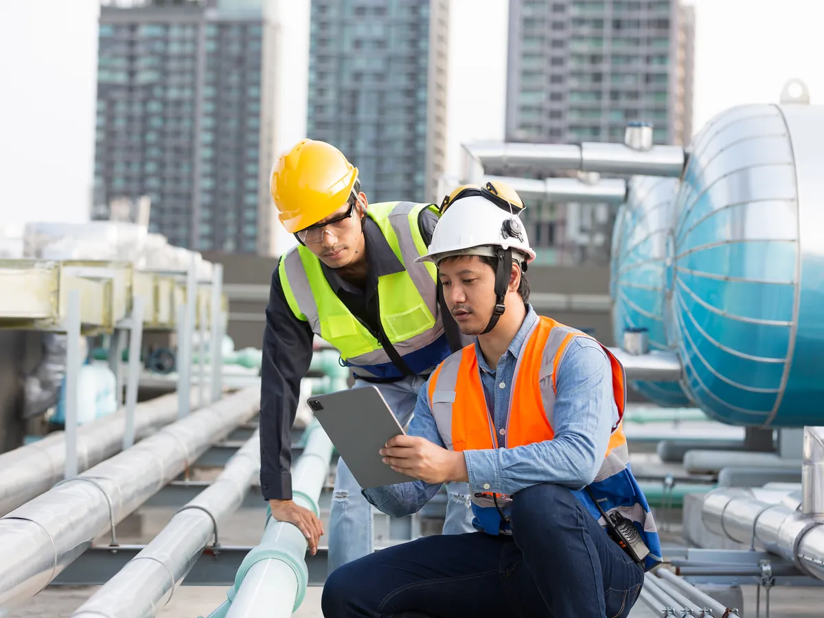 Two utility engineers reviewing plans on a tablet at a water infrastructure site